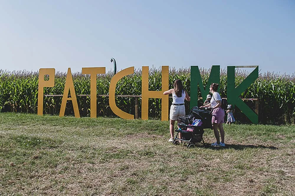 Visitors by the Patch MK sign in front of the maize field